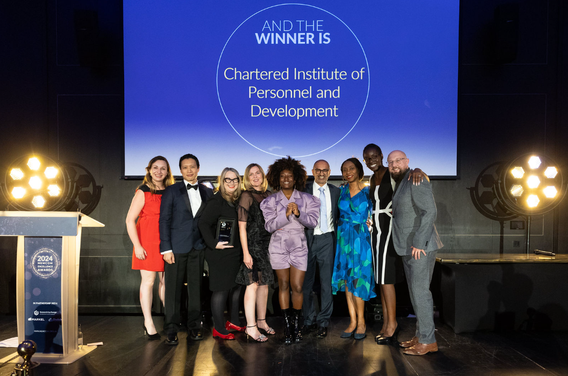 A group of colleagues smile at the camera after accepting an award on stage