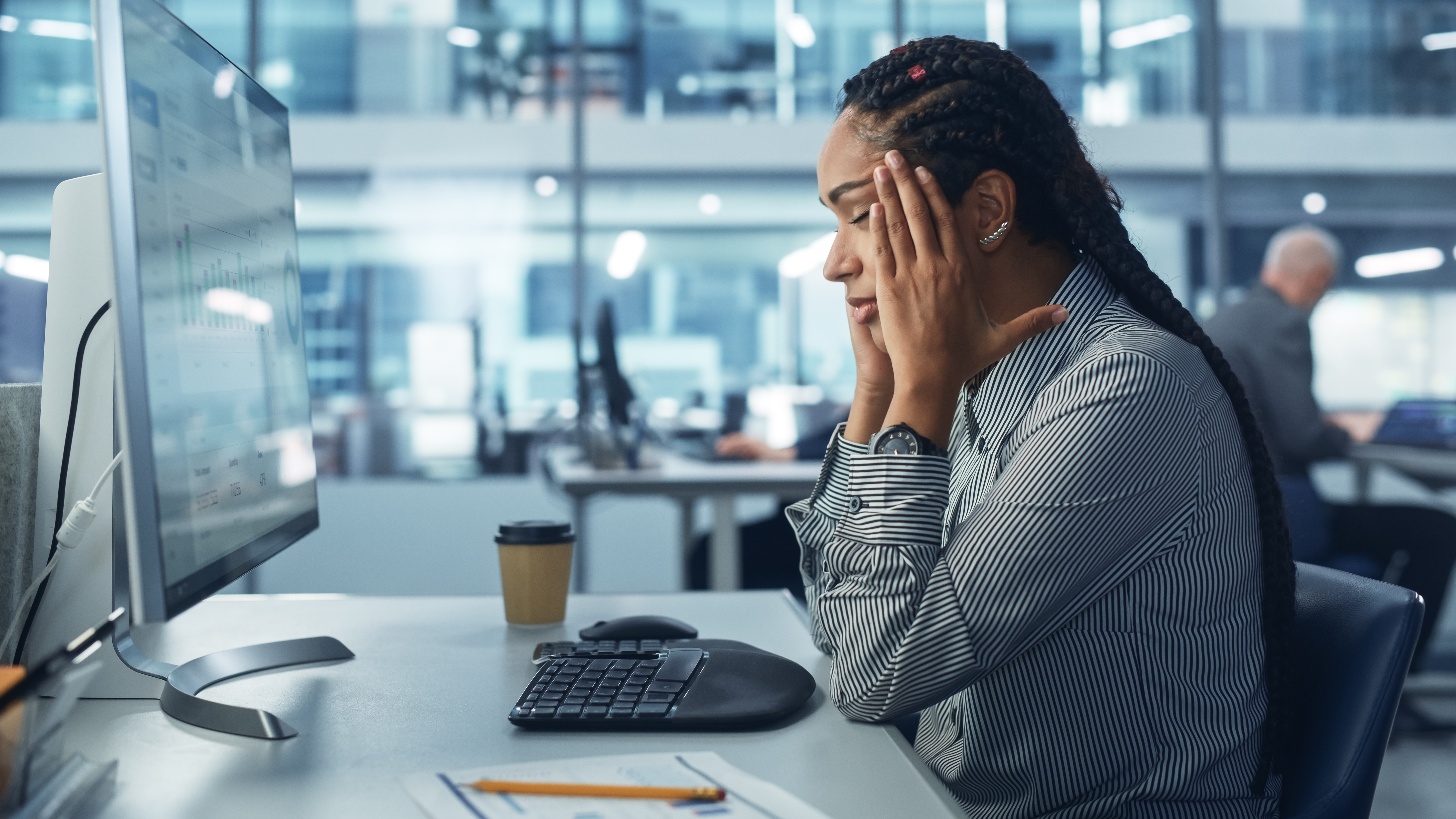 woman sat at computer with head in her hands