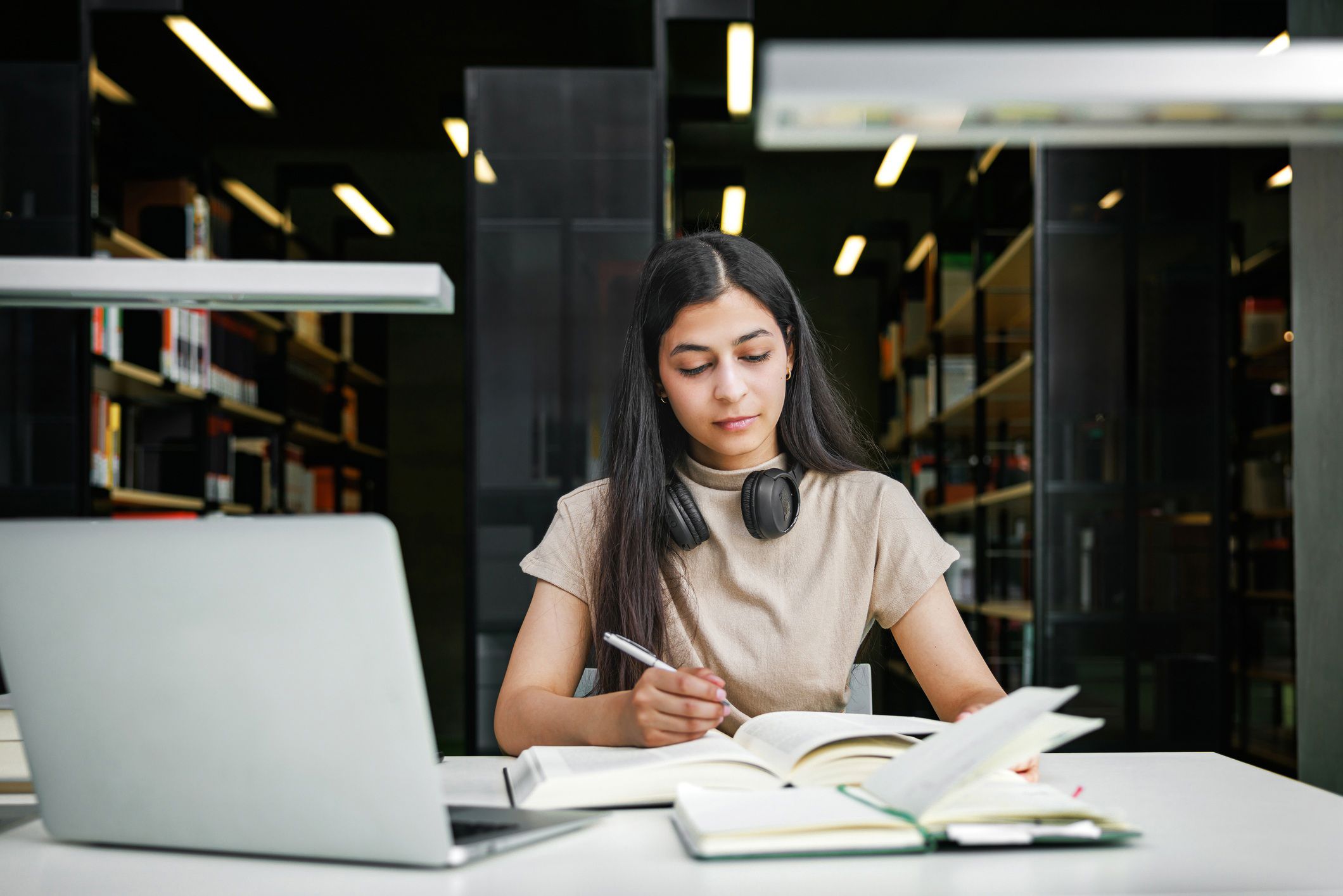 Woman sitting at a laptop with notebooks